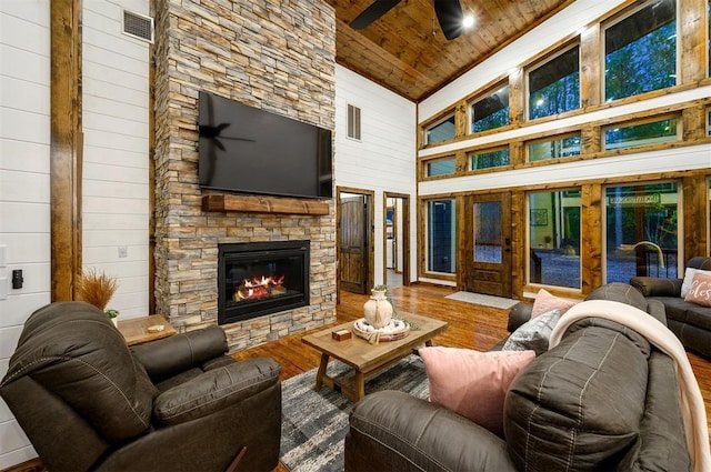 living room with wooden walls, high vaulted ceiling, wooden ceiling, a fireplace, and hardwood / wood-style floors