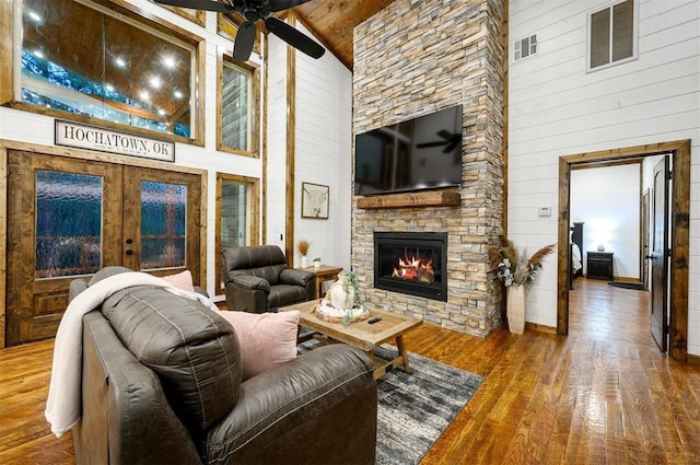 living room featuring wood walls, high vaulted ceiling, and hardwood / wood-style flooring