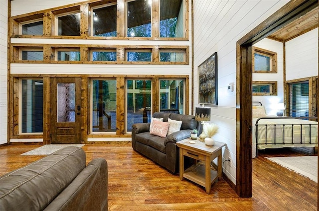 living room with wood walls, wood-type flooring, and high vaulted ceiling