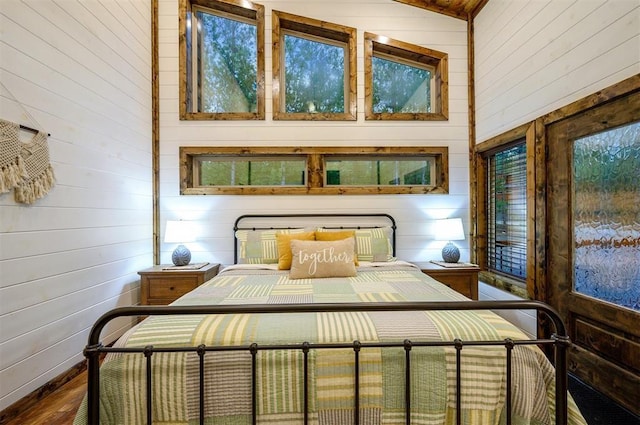 bedroom featuring wood-type flooring, high vaulted ceiling, and wooden walls