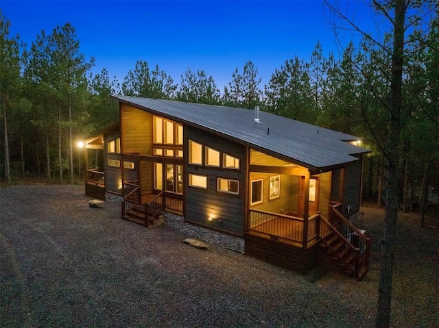 back house at dusk featuring covered porch