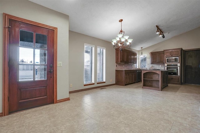 kitchen featuring pendant lighting, an inviting chandelier, vaulted ceiling, tasteful backsplash, and stainless steel appliances