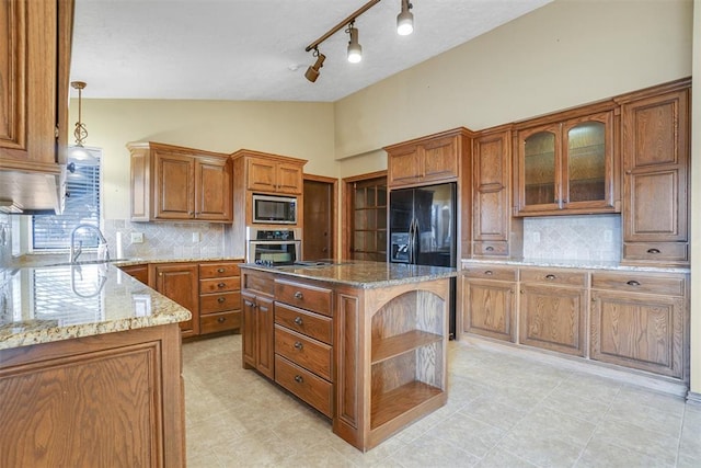 kitchen with light stone counters, a center island, stainless steel appliances, and decorative light fixtures