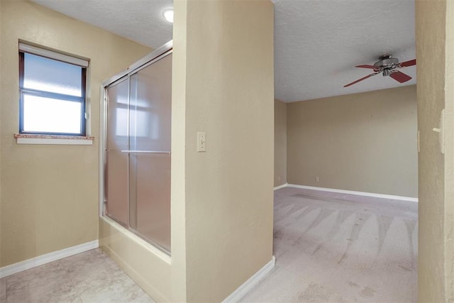 bathroom with shower / bath combination with glass door, a textured ceiling, and ceiling fan