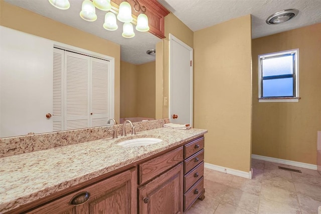 bathroom with a textured ceiling, vanity, and tile patterned floors