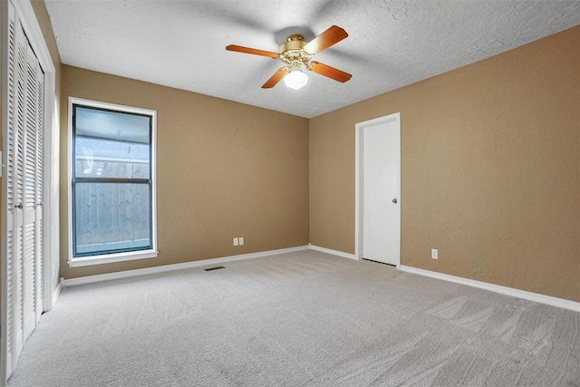 unfurnished room featuring ceiling fan, light colored carpet, and a textured ceiling