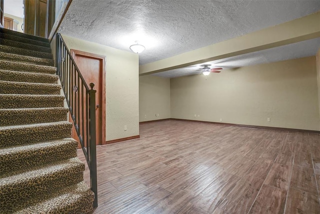 basement featuring ceiling fan, hardwood / wood-style floors, and a textured ceiling