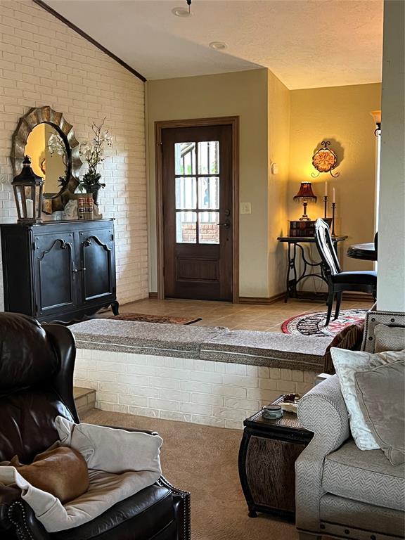 living room with lofted ceiling and brick wall