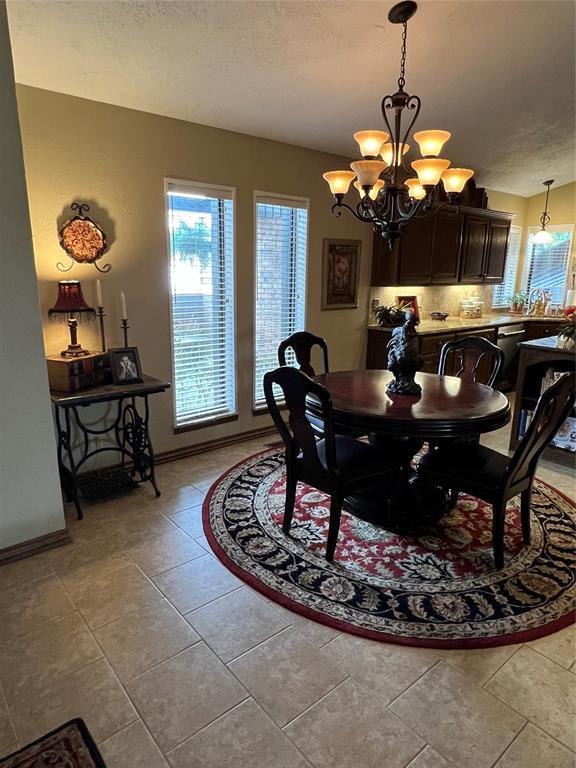 tiled dining space with a textured ceiling and a notable chandelier