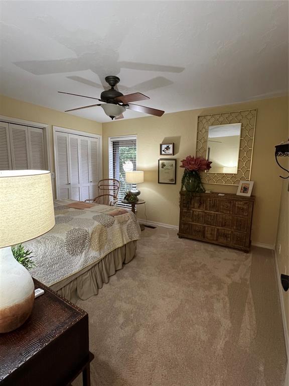 carpeted bedroom featuring two closets and ceiling fan