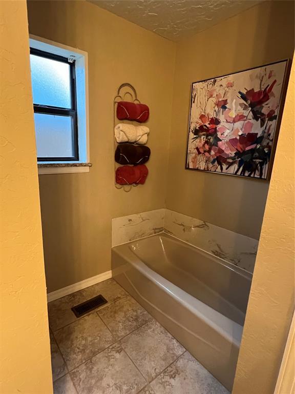 bathroom featuring tile patterned flooring, a textured ceiling, and a tub