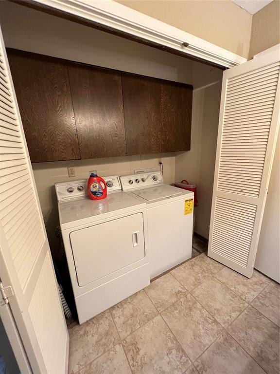 clothes washing area with light tile patterned flooring, cabinets, and independent washer and dryer