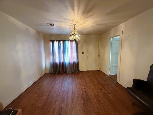 spare room with dark hardwood / wood-style flooring and a notable chandelier