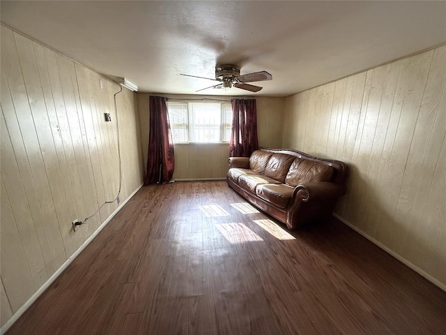 unfurnished living room with dark hardwood / wood-style floors, ceiling fan, and wooden walls