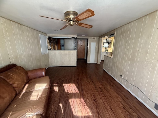 unfurnished living room with dark hardwood / wood-style floors, wood walls, and ceiling fan