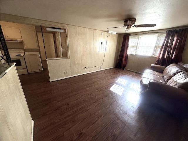 living room featuring ceiling fan, wood walls, and dark wood-type flooring