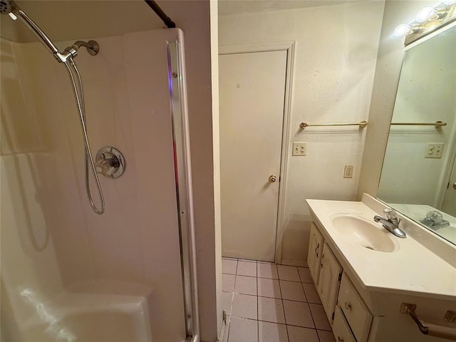 bathroom with tile patterned floors, vanity, and walk in shower
