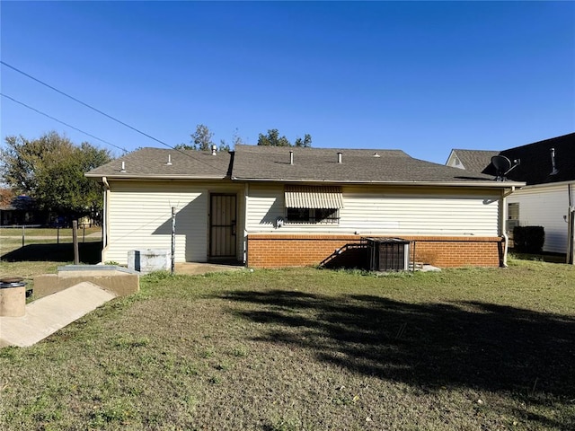rear view of property featuring central AC unit and a lawn