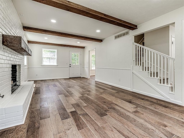 unfurnished living room featuring a fireplace, hardwood / wood-style floors, and beamed ceiling