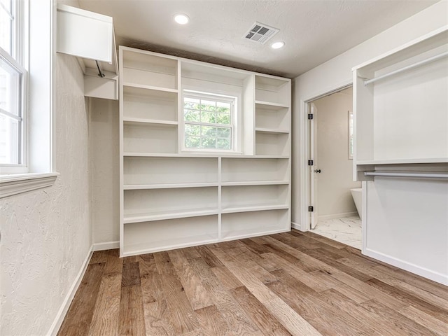 walk in closet with light hardwood / wood-style flooring