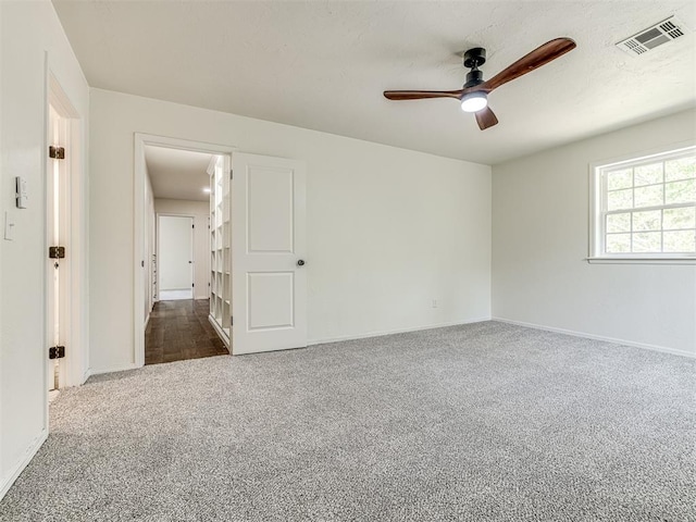 unfurnished room with ceiling fan and dark carpet