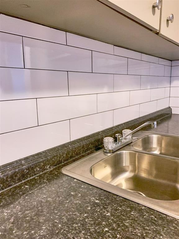 details featuring decorative backsplash, sink, and dark stone counters