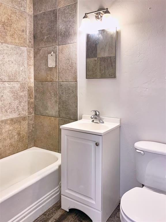 full bathroom featuring wood-type flooring, vanity, toilet, and tiled shower / bath