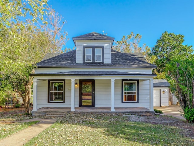 view of front of home with covered porch, a garage, and a front lawn