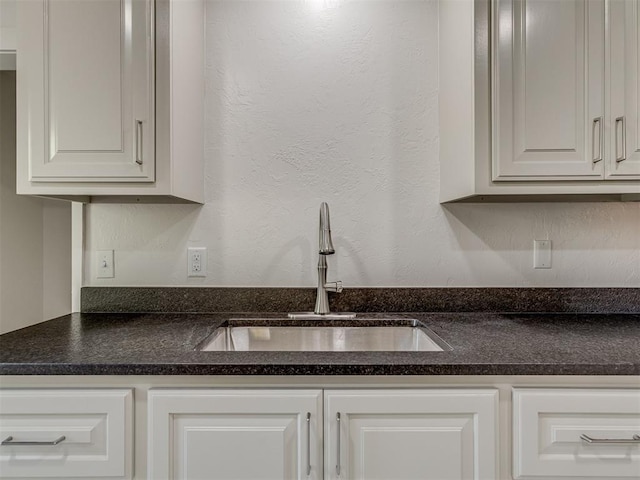 309 S 6th St, Kingfisher, OK 73750 - kitchen featuring a sink, dark countertops, white cabinetry, and a textured wall