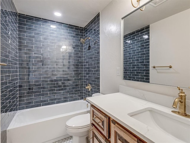 full bathroom featuring tile patterned flooring, vanity, tiled shower / bath combo, and toilet