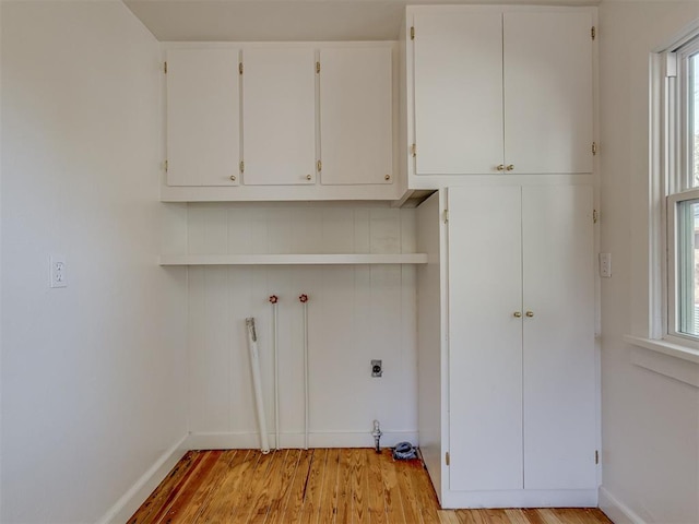 laundry room with cabinets, hookup for an electric dryer, a healthy amount of sunlight, and light hardwood / wood-style floors