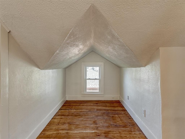 309 S 6th St, Kingfisher, OK 73750 - additional living space with a textured ceiling, wood finished floors, vaulted ceiling, a textured wall, and baseboards