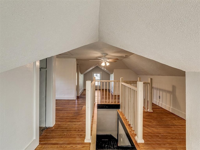 additional living space with hardwood / wood-style flooring, lofted ceiling, and a textured ceiling