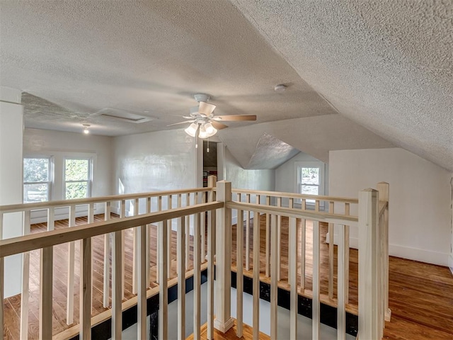 hall featuring a textured ceiling, wood-type flooring, and vaulted ceiling