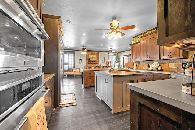 kitchen with decorative backsplash, oven, ornamental molding, and a kitchen island