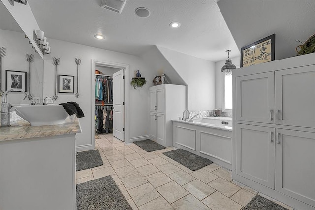 bathroom featuring tile patterned flooring, vanity, a bath, and a textured ceiling