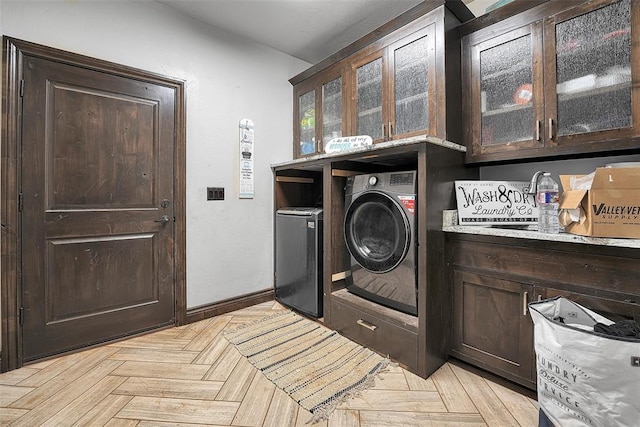 laundry room featuring washer and dryer, cabinets, and light parquet floors