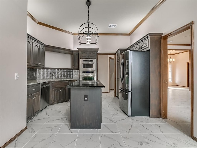 kitchen with an inviting chandelier, appliances with stainless steel finishes, dark stone countertops, a kitchen island, and dark brown cabinetry