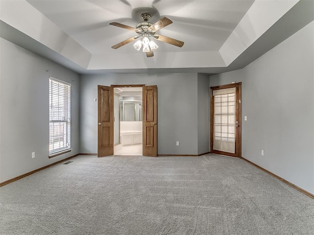 unfurnished bedroom featuring ceiling fan, light colored carpet, and a raised ceiling