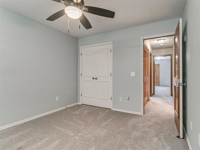 unfurnished bedroom featuring ceiling fan, light colored carpet, and a closet