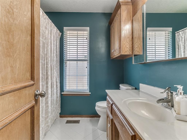 bathroom featuring toilet, vanity, and tile patterned flooring