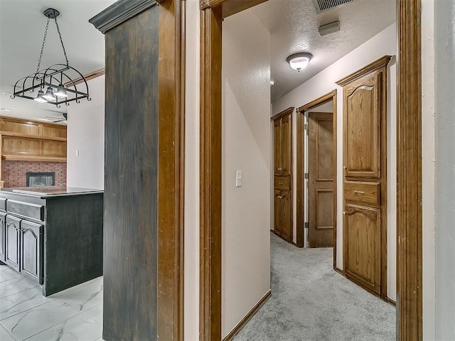 corridor with a textured ceiling and light carpet