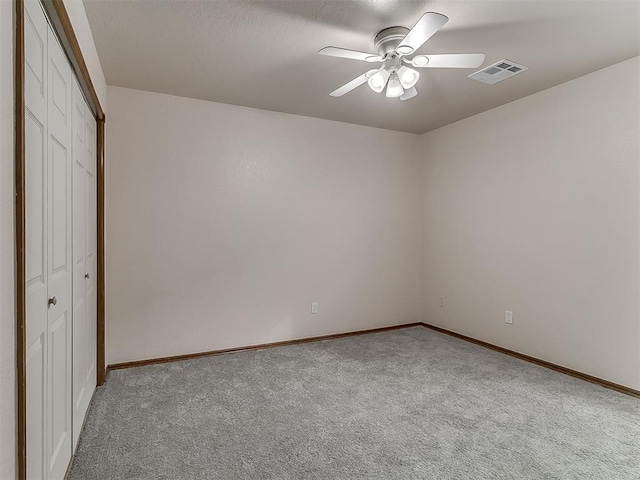 unfurnished bedroom with ceiling fan, light colored carpet, and a closet