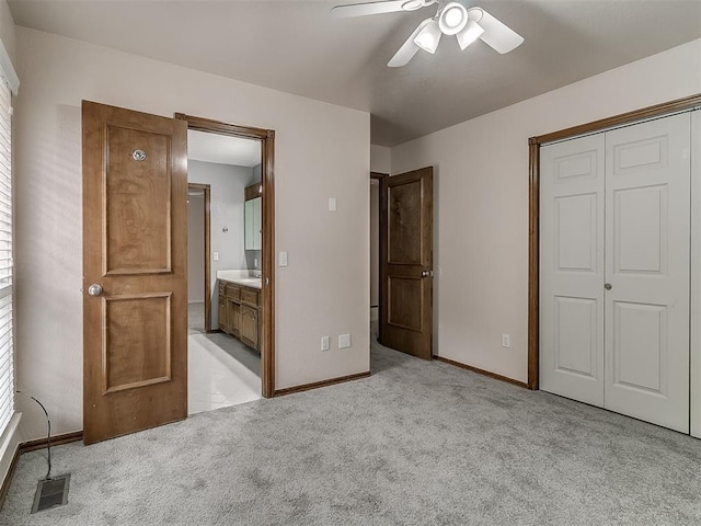 unfurnished bedroom featuring ceiling fan, connected bathroom, a closet, and light carpet