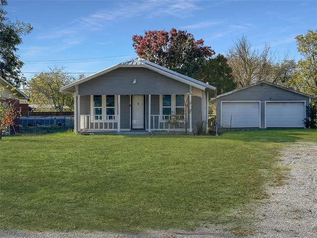 view of front facade featuring covered porch, an outbuilding, a garage, and a front yard