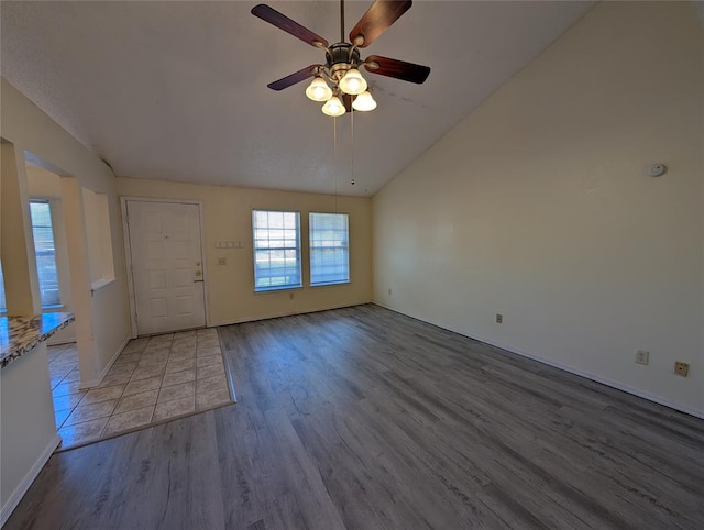 interior space with ceiling fan, wood-type flooring, and vaulted ceiling