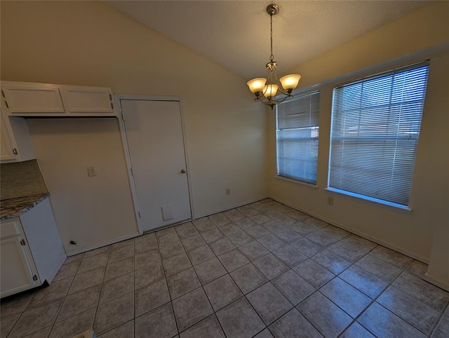 unfurnished dining area featuring vaulted ceiling, light tile patterned floors, and a chandelier