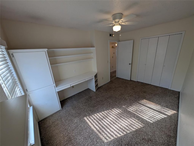 unfurnished bedroom featuring dark colored carpet, ceiling fan, and a closet