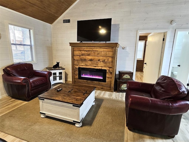 living room with a stone fireplace, wooden ceiling, wood-type flooring, and vaulted ceiling