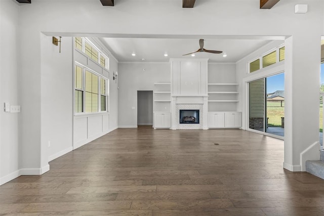 unfurnished living room featuring beam ceiling, a fireplace, baseboards, and wood finished floors